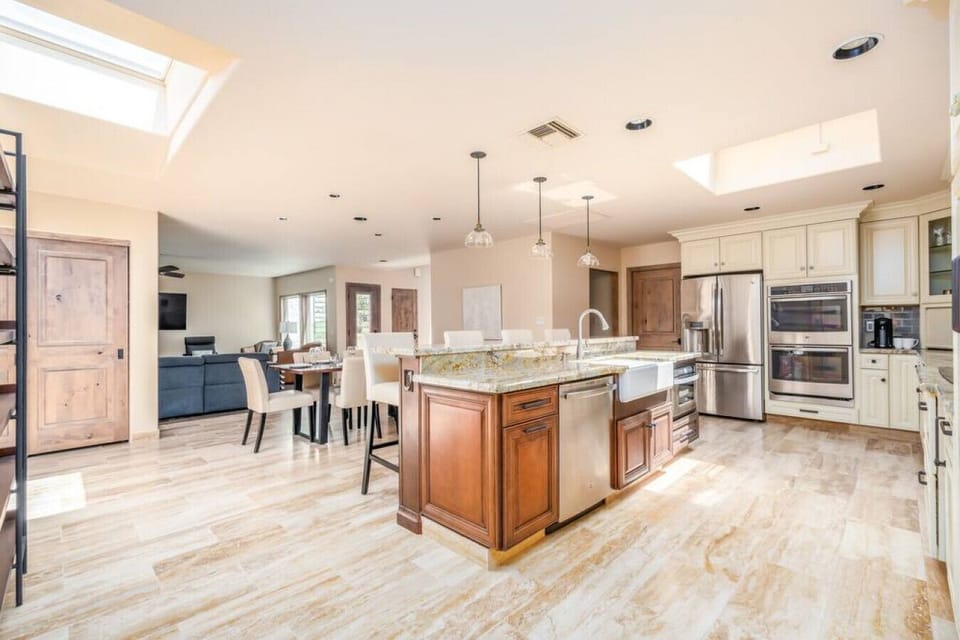Spacious chef’s kitchen with granite island, stainless steel appliances, and open flow to the dining and living areas.