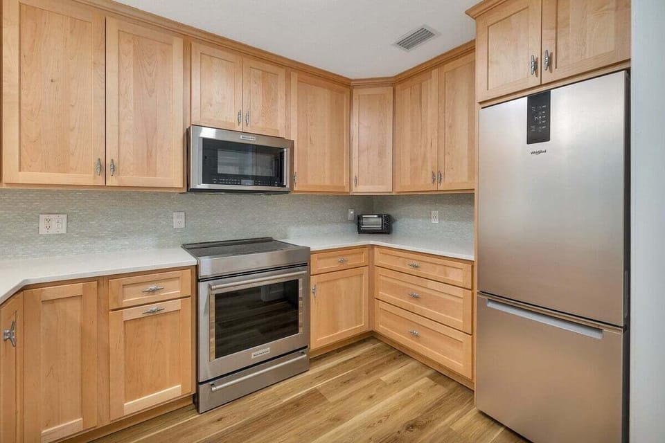 Wood kitchen with stainless appliances and refrigerator