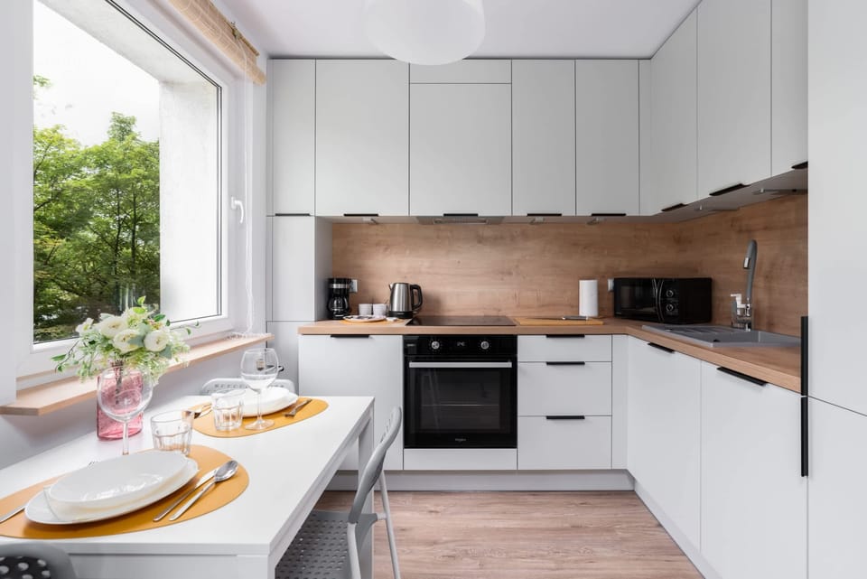 A bright, modern kitchen with white cabinetry, wooden countertops, and a breakfast setup.

