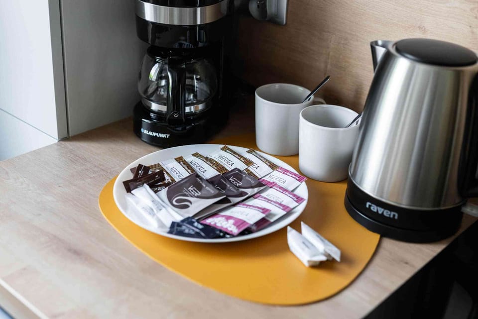 A close-up of a coffee and tea setup, featuring a kettle and stylish serving tray.

