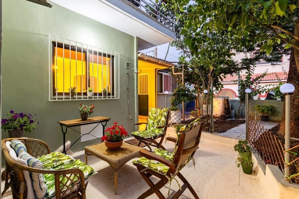 Enjoy a Drink on the Patio under the Olive Tree – A peaceful outdoor setting surrounded by lush greenery, perfect for relaxing moments any time of day.