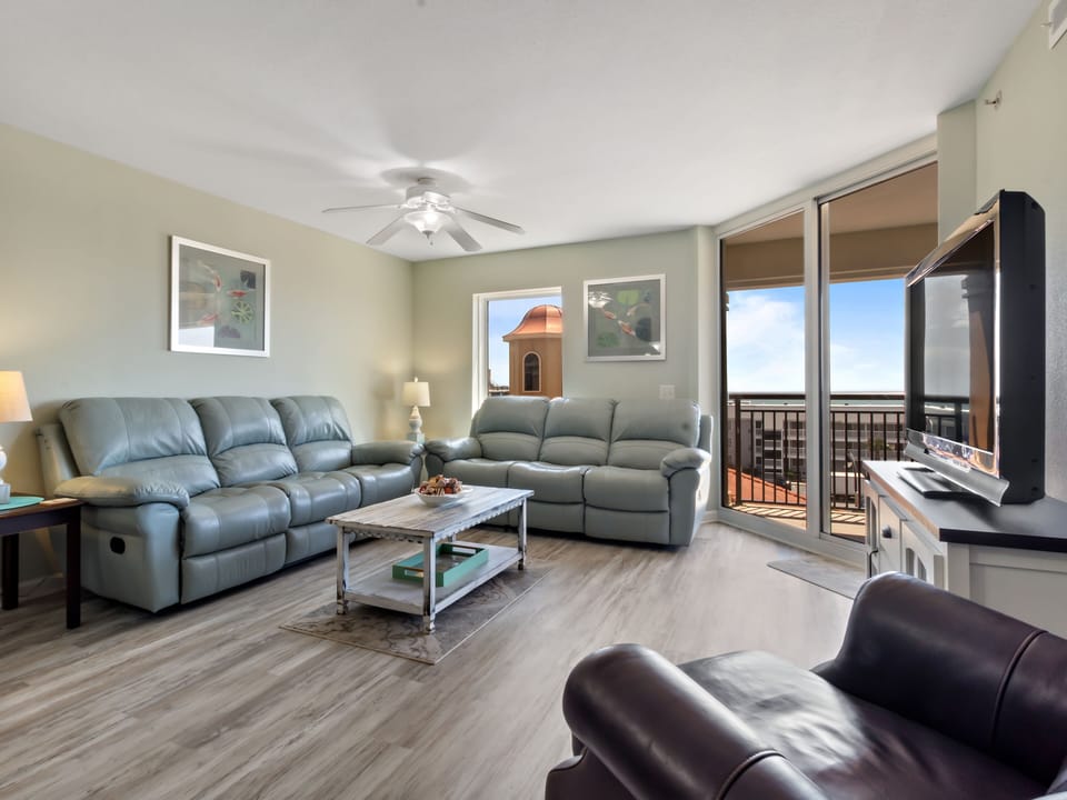 Sink into plush leather sofas while enjoying natural light streaming through your private balcony doors in this spacious, comfortable living room.
