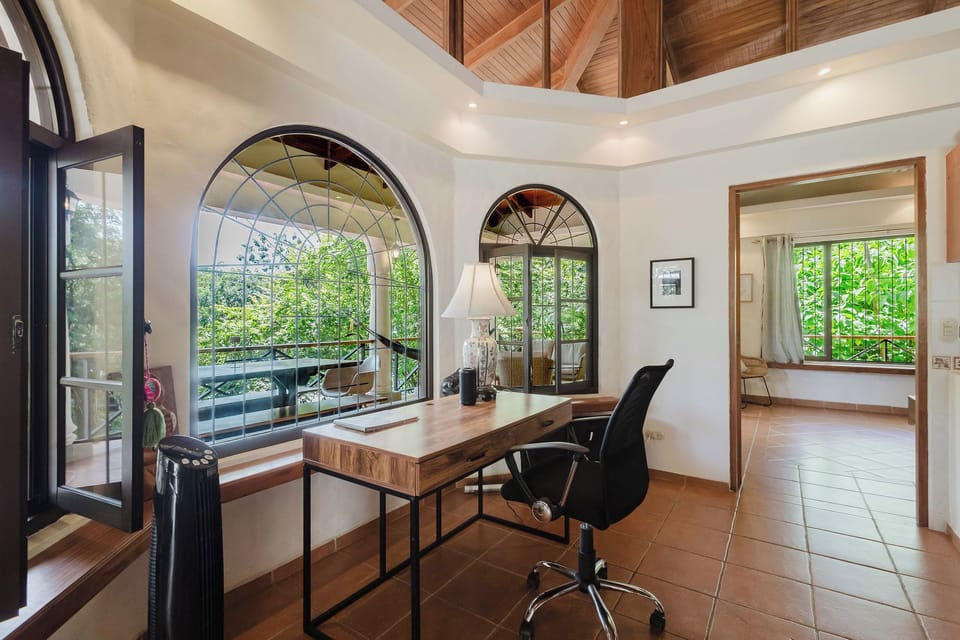 Bright home office with arched windows, garden views, and soaring wood ceilings