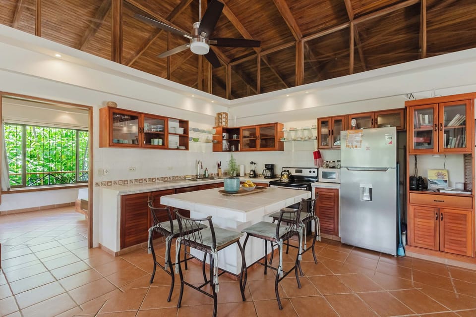 Spacious tropical kitchen with vaulted wood ceilings and island seating