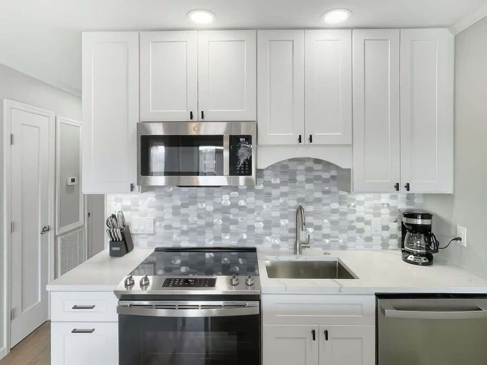 A sleek, updated kitchen equipped with white cabinetry and stainless steel appliances