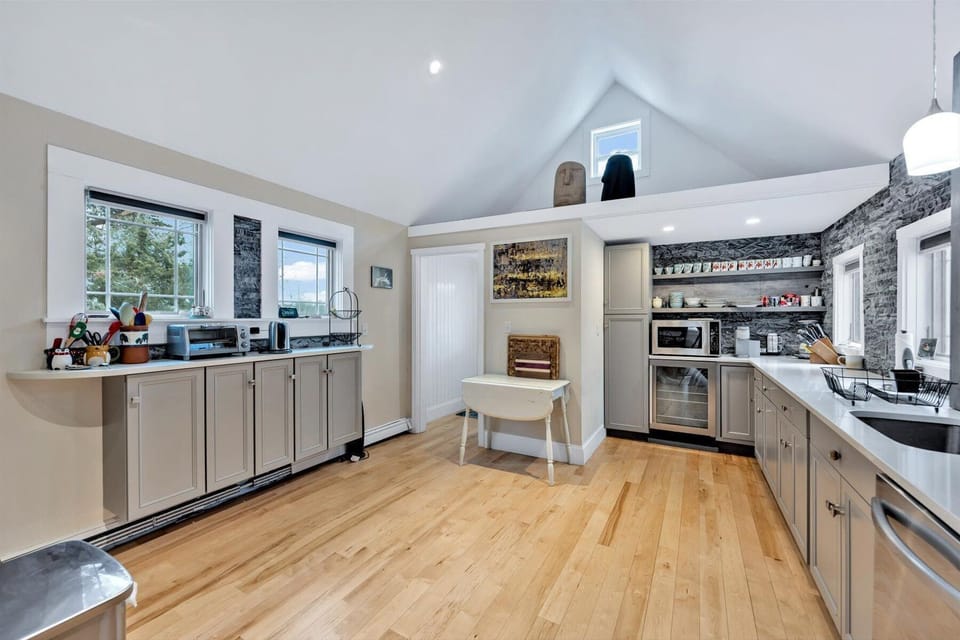 Kitchen with gray cabinets, dark stone wall accents, and stainless steel appliances