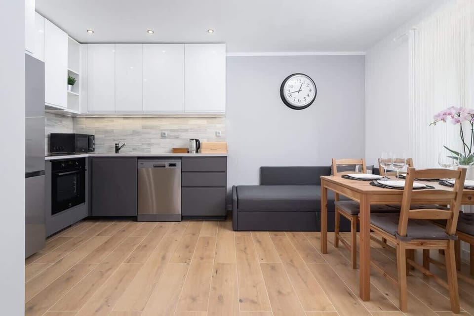 A modern dining and kitchen area with a wooden table, white cabinetry, and minimalistic decor.

