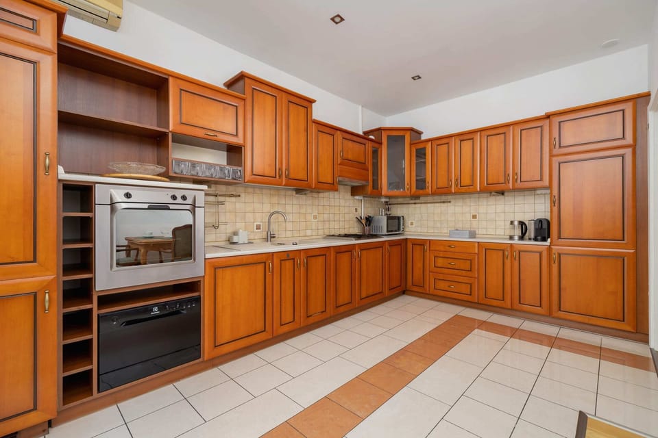 A modern kitchen with wooden cabinetry, a built-in oven, and ample countertop space.

