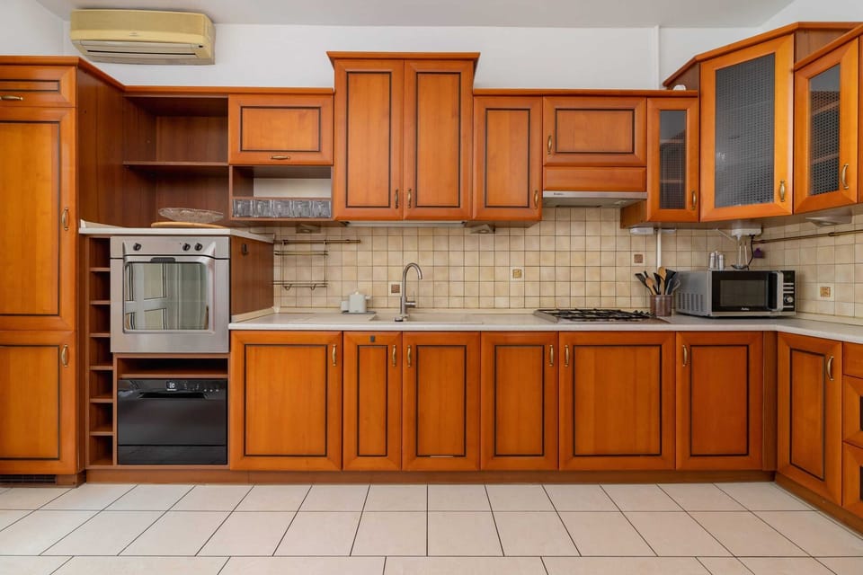 A fully equipped kitchen showcasing traditional wood design and tiled backsplash.

