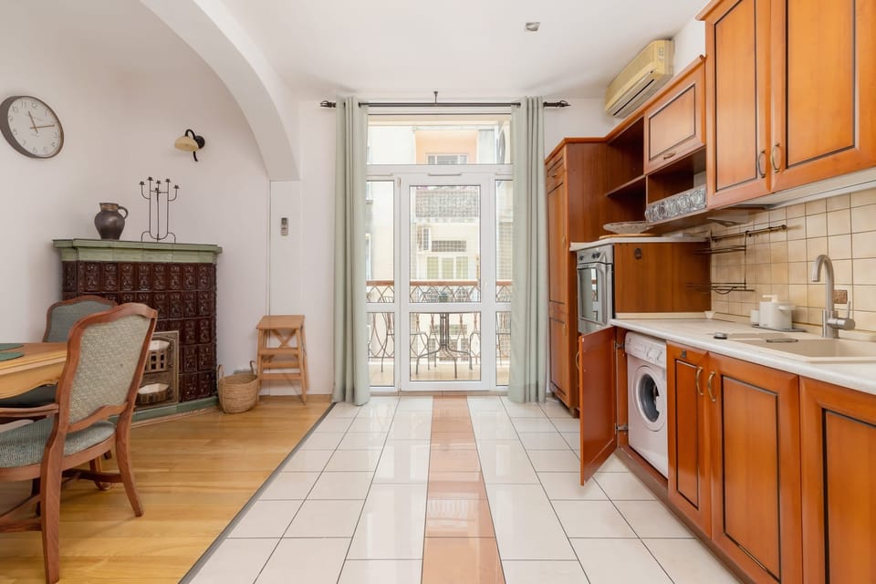 A dining area with antique furniture, opening into a spacious and bright kitchen.

