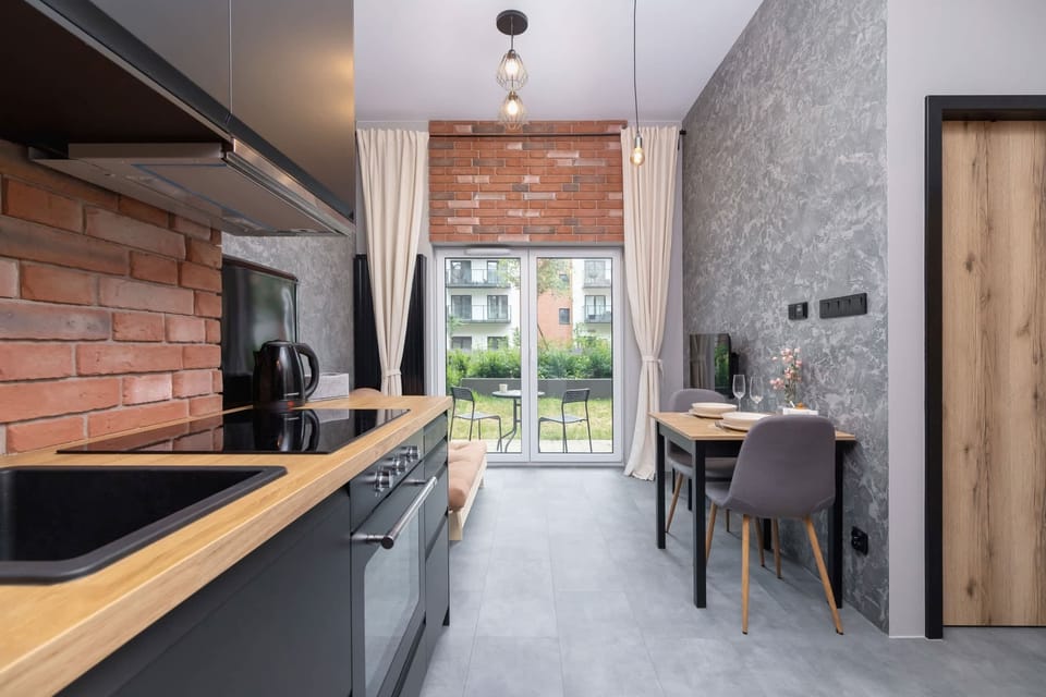 A view of the kitchen and living area with an industrial style, highlighted by exposed brick.

