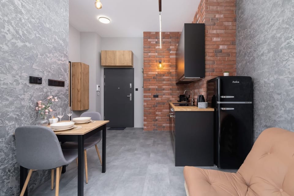 A kitchen and dining space with exposed brick walls, modern appliances, and industrial design.

