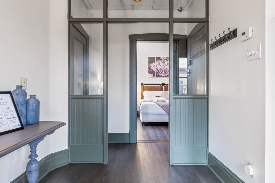 The entry hall uses handsome glass-paneled doors to create an open connection between the bedroom and living spaces.