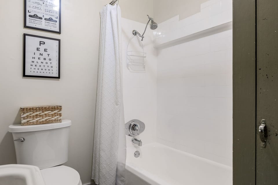 A clean tub-and-shower combination with grab bars, fresh towels, and a crisp white curtain completes the bathroom.