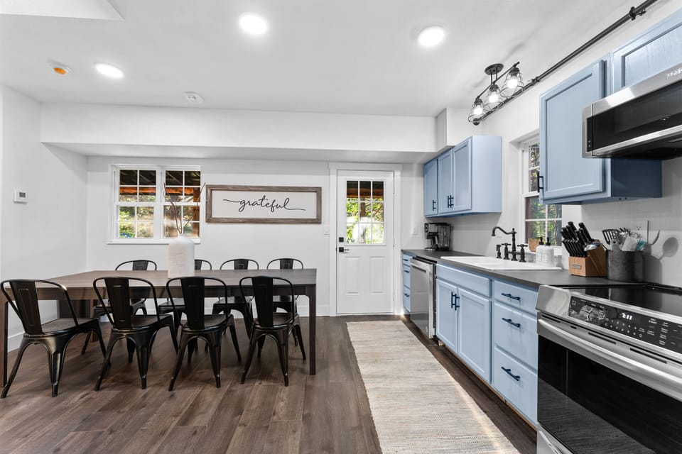 The modern kitchen has all-new appliances - microwave, induction stove/oven, dishwasher, and fridge. It's connected to the dining area with seating for 8.