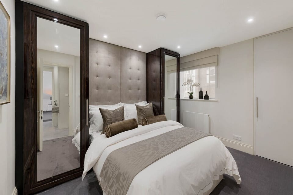 Bedroom — king bed with bespoke fitted wardrobes, quality carpet, Smart TV, blackout Roman blinds, and in-room safety deposit box