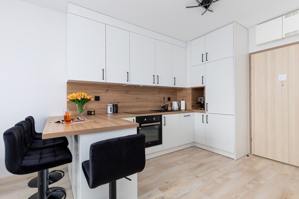 A dining and kitchen area featuring a bar counter with black stools and sleek cabinetry.


