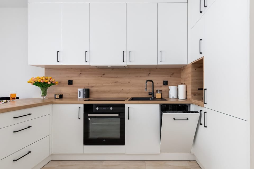 A fully equipped kitchen with white cabinets, wooden countertops, and modern appliances.

