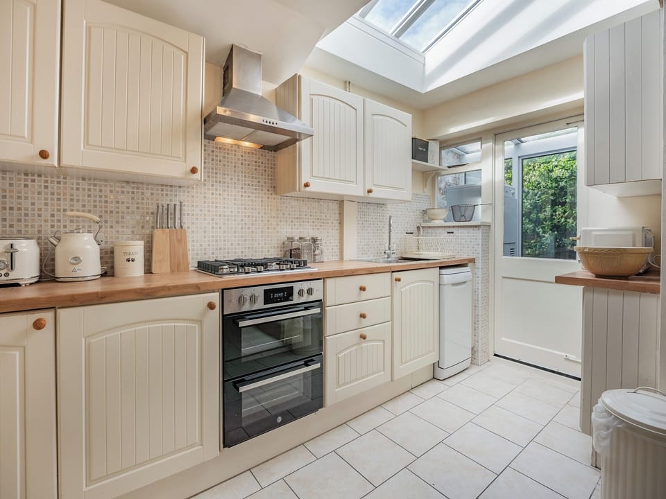 Open plan kitchen with Lavazza coffee pod machine and everything you need for cooking. Door leads to utility room with washing machine, iron etc | Greenfield Cottage 1866, Worthing