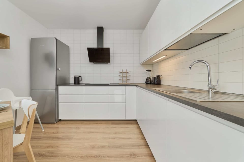 A sleek kitchen with white cabinetry, stainless steel appliances, and wooden accents.

