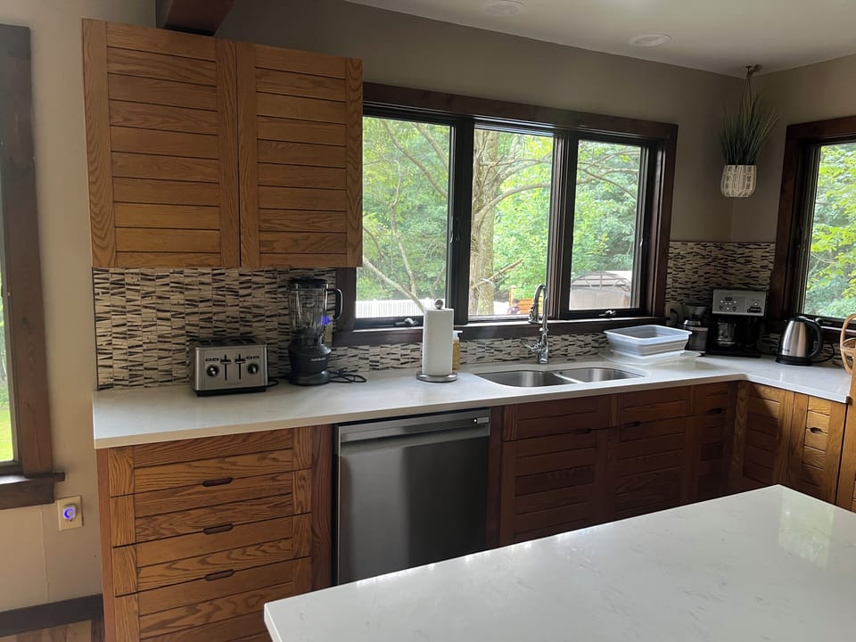 Modern kitchen with a big marble counter and new stainless steel appliances. 