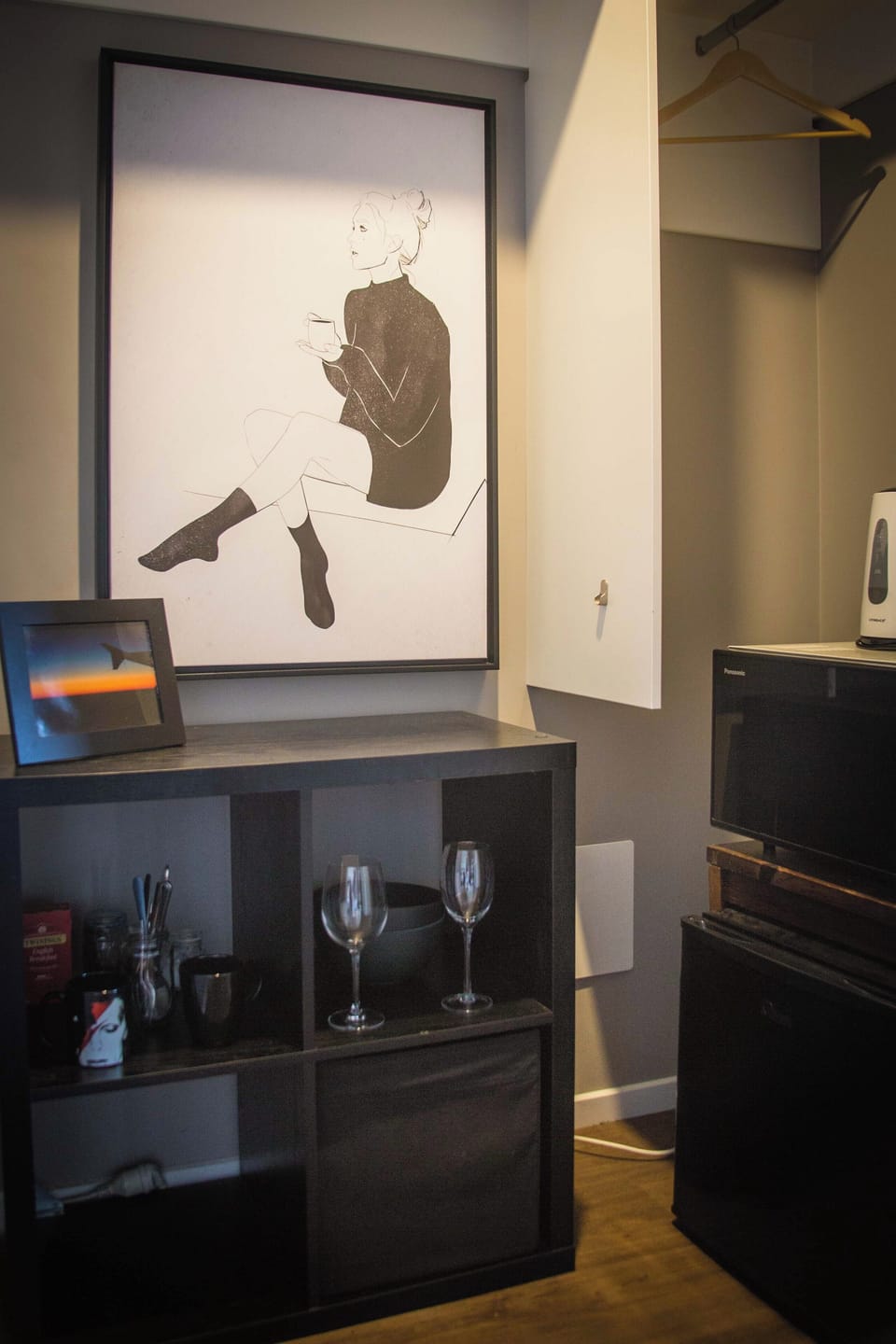 Small kitchenette with microwave, fridge, wine glasses, coffee, and tea.
