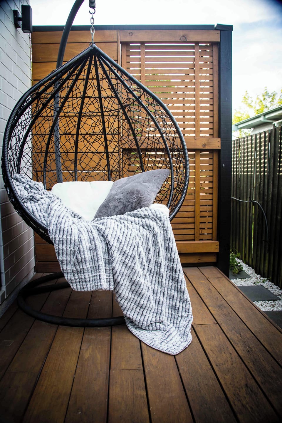 Outdoor area with deck, lattice covering for privacy, and a cozy egg chair. 