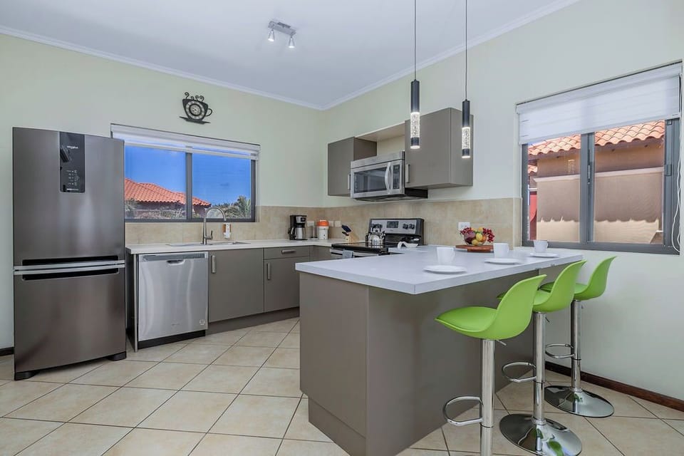 Modern kitchen with clean finishes, stainless steel appliances, and a bright breakfast bar—perfect for casual dining or morning coffee before heading out to explore Aruba. Message us for details.