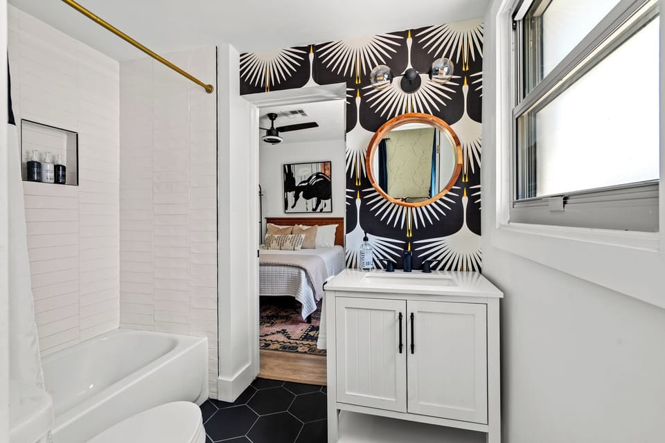 Bold wallpaper adds a glam touch to this modern, shared bathroom.