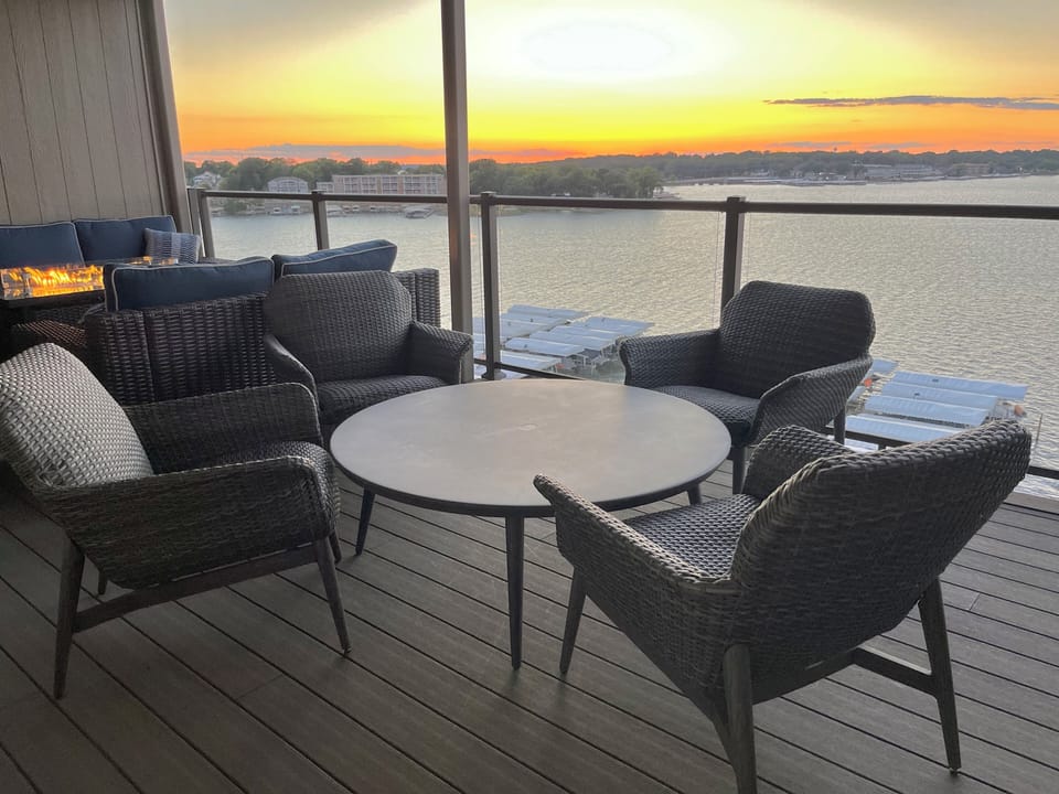 Top floor covered deck w/ expansive lake views, fire table, plush seating for 12