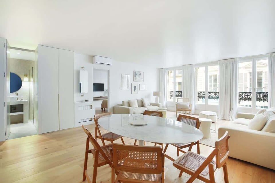 Salon avec 2 canapés lits et cuisine américaine équipée, coin repas avec table et chaises