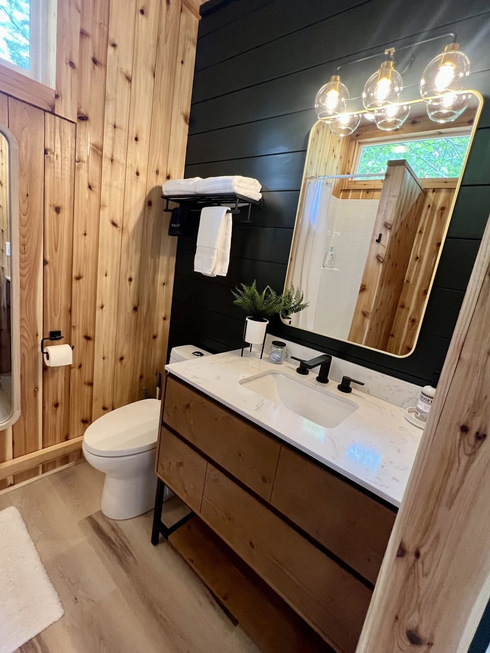 The large bathroom has a full-size vanity, full-size shower, flush toilet, bench/changing area, and full size mirror.  