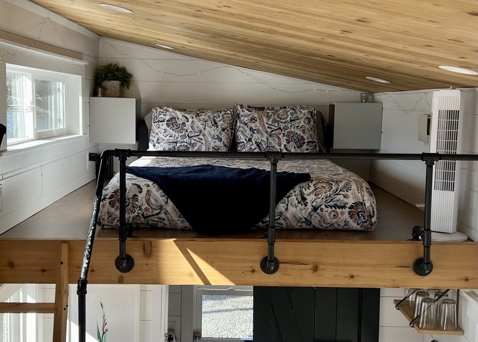 The loft area includes a comfy queen-size bed and a view of the trees and lake out the window.