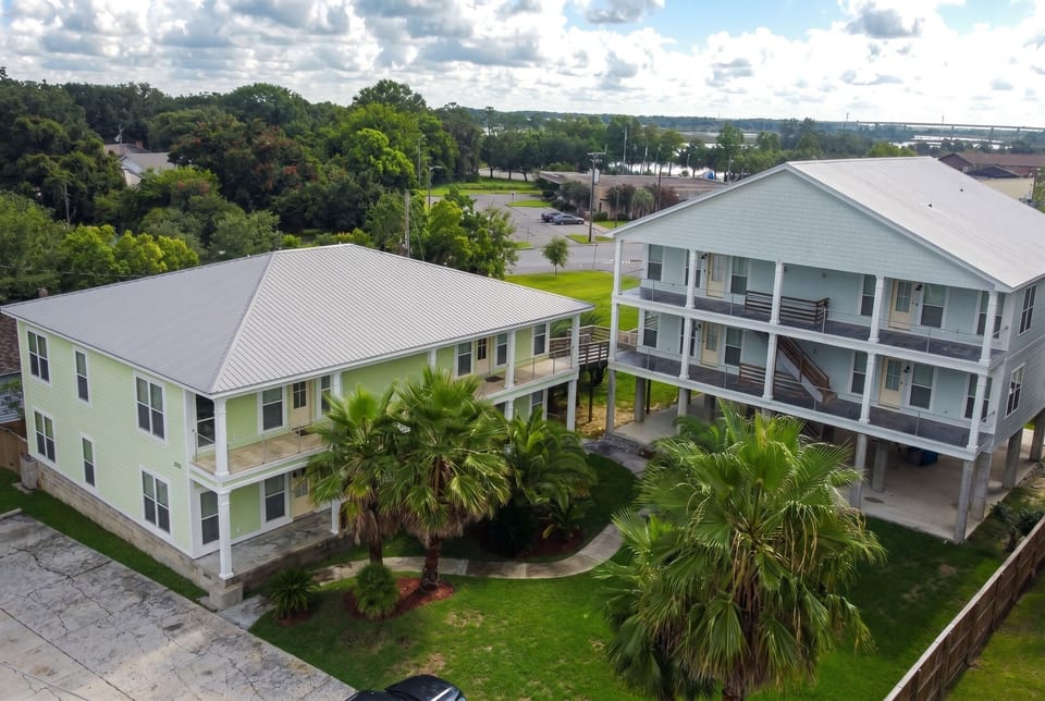Aerial view of elevated coastal homes with palms and spacious balconies
