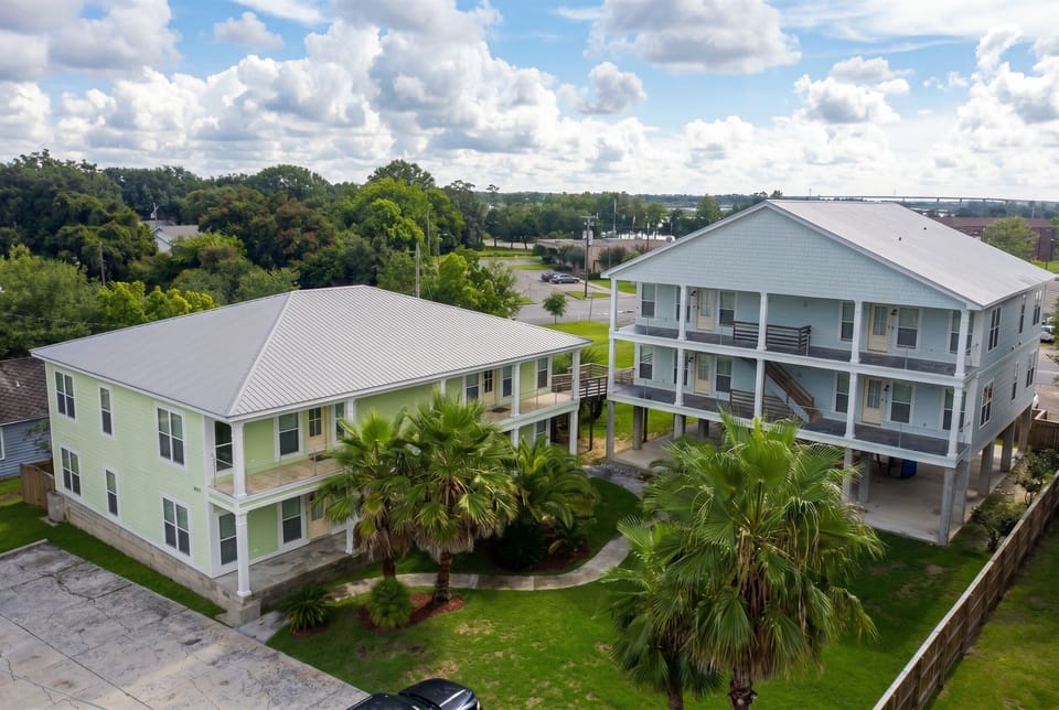 Aerial view of spacious coastal buildings with balconies and palm-lined grounds