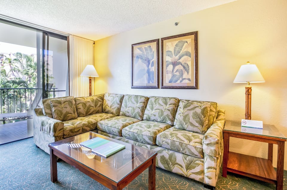 Relax in your tropical-themed living room, complete with a plush sofa, tropical artwork, and natural light streaming in from your private balcony with garden views.