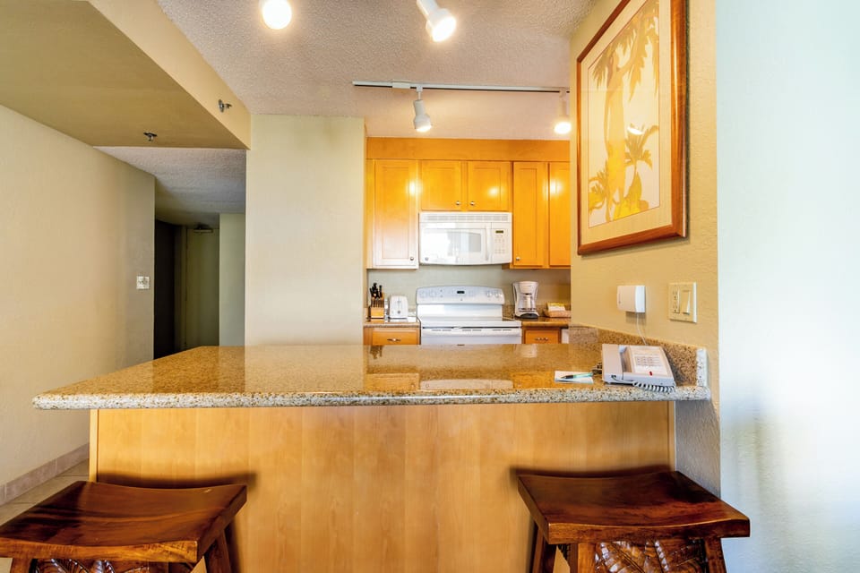 Your spacious kitchen features warm wood cabinetry, granite countertops, and a breakfast bar with seating—perfect for preparing meals and enjoying your morning coffee in comfort.