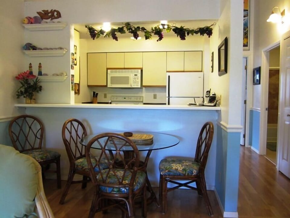 You'll love preparing meals in this fully equipped kitchen featuring modern appliances and a convenient breakfast bar. The adjacent dining area with its charming glass-top table is perfect for enjoying your morning coffee or evening meals.