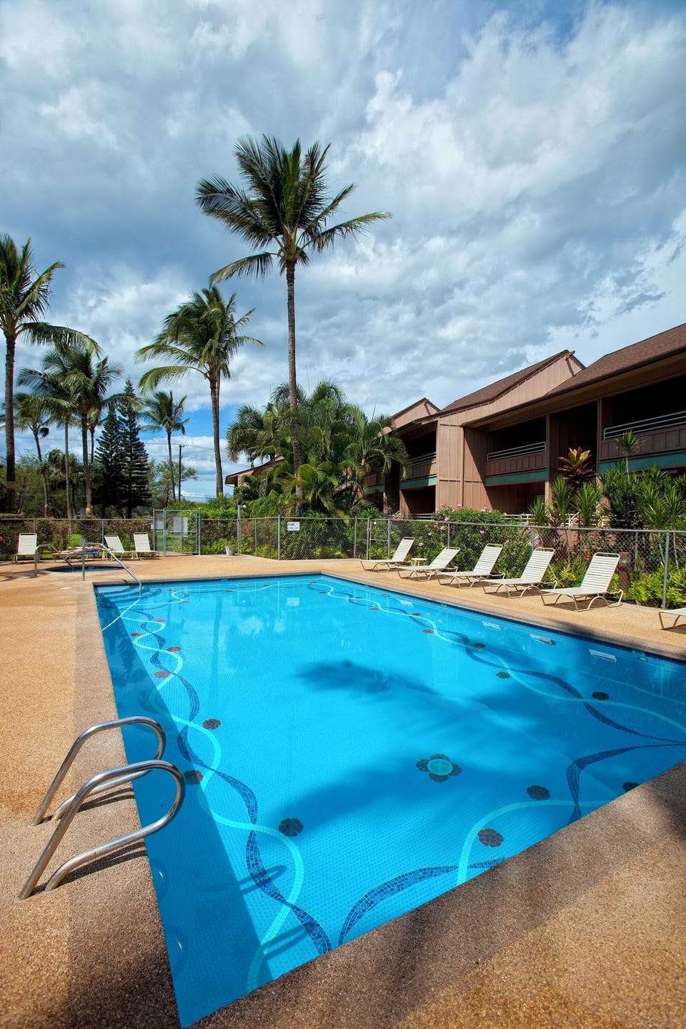 The tropical pool complex features a two-tier design with loungers set among swaying palms, creating a secluded oasis beneath open skies.