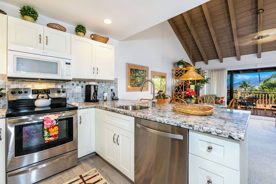 Your vacation kitchen blends style and function with granite counters, stainless appliances, and tropical views through large windows that frame paradise beyond.
