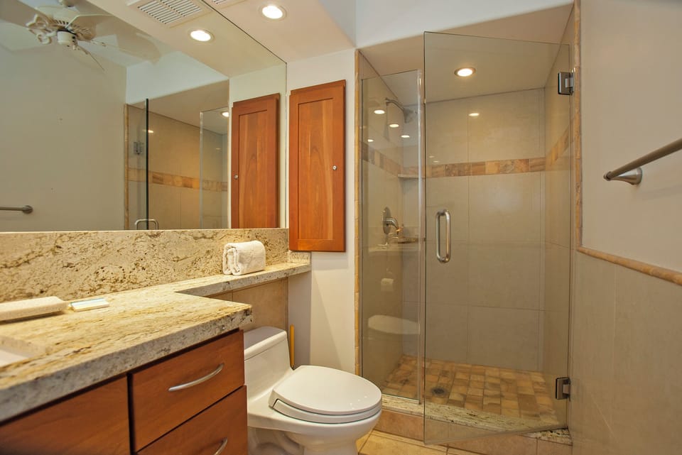 Relax and refresh in your private bathroom, featuring a spacious walk-in shower, elegant granite countertops, and warm wood cabinetry for a soothing retreat after a day of exploring.