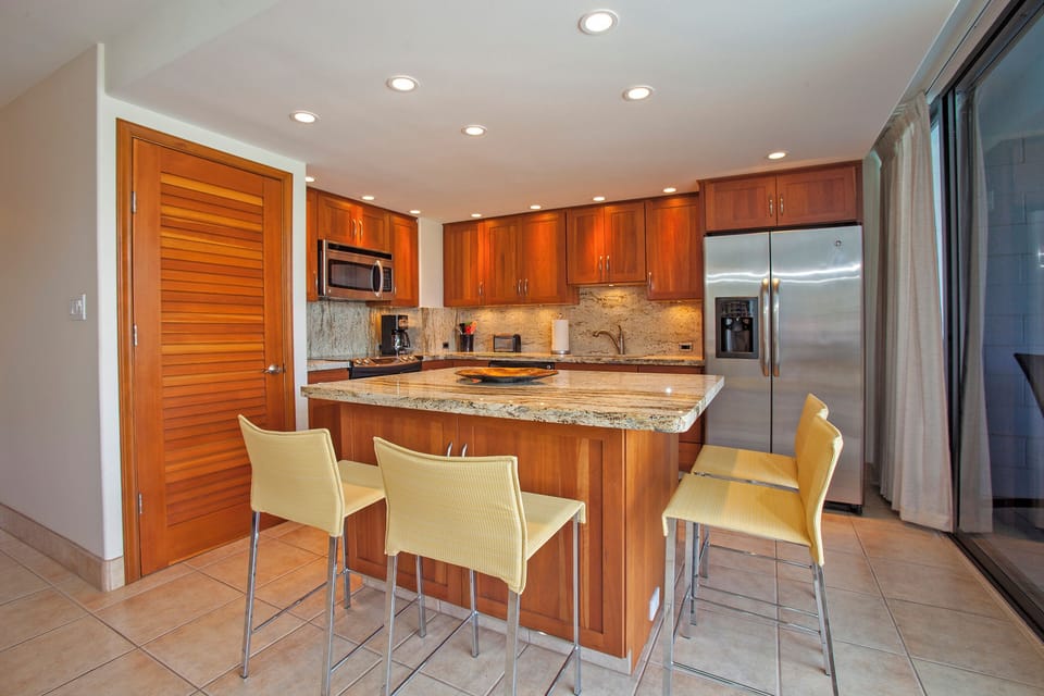 Your island is perfect for morning coffee or quick bites, anchored by granite countertops and warm wood cabinetry, with stainless steel appliances completing this well-appointed kitchen.