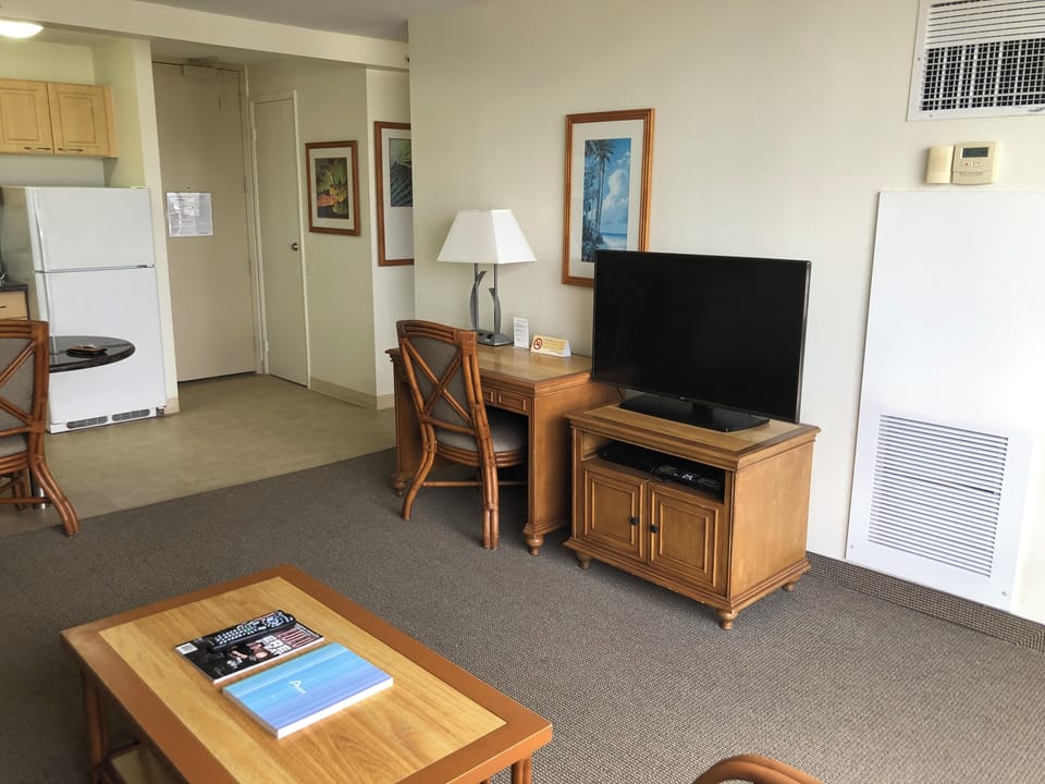 Your comfortable living space blends function with relaxation—unwind with coastal artwork above the TV, enjoy meals at your desk, and prepare snacks in the kitchenette nearby.