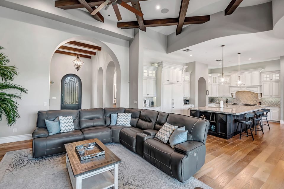 Living Room with Leather Reclining Sectional, Smart TV Accented with Criss Crossed High Wood Beam Ceilings