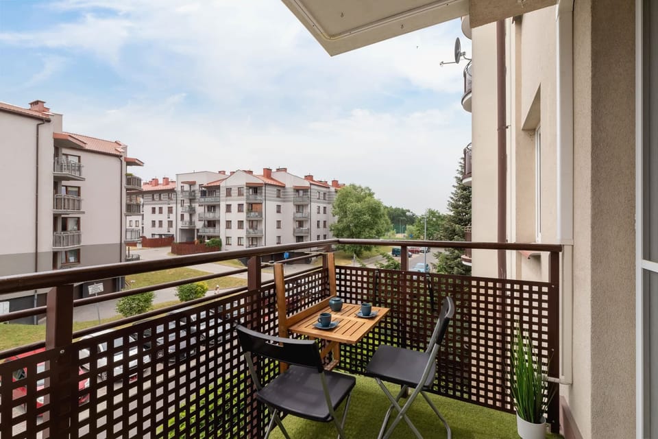 A balcony with a table, chairs, and a view of the surrounding neighborhood.

