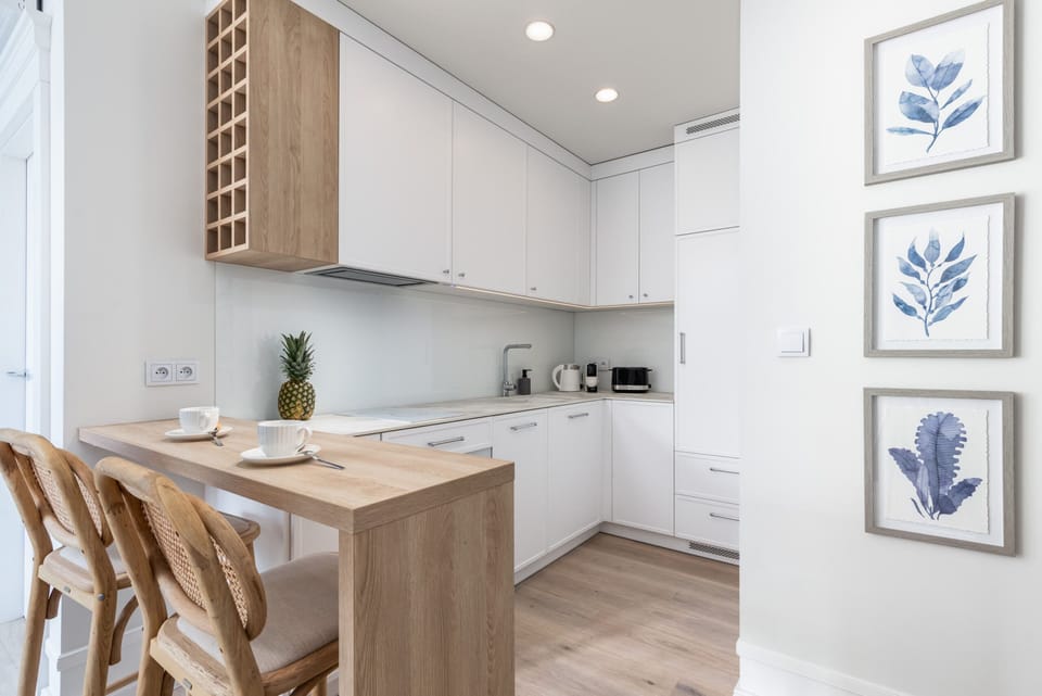 Fully equipped kitchen with white cabinetry, wooden accents, and stylish botanical wall art for a cozy vibe.

