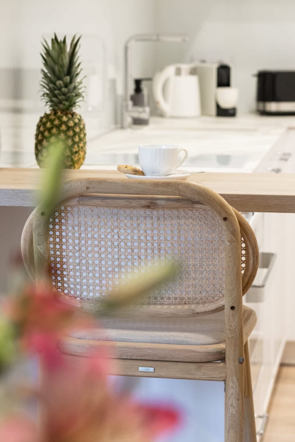 Close-up of a dining table with a rattan chair and a decorative pineapple centerpiece, adding a tropical touch.

