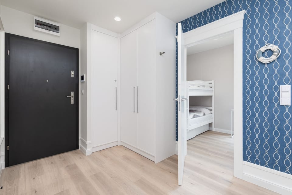 Entryway with modern design elements, including a full-length mirror, sleek black door, and subtle nautical details.






