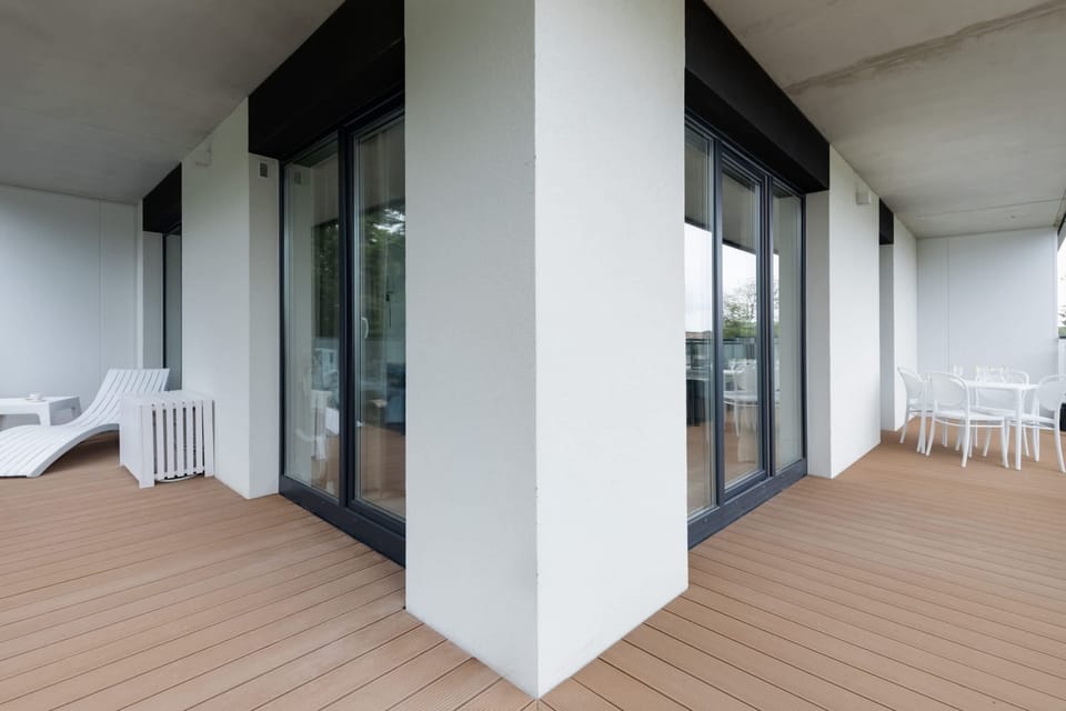 Balcony area with modern glass railings, spacious wooden flooring, and scenic views, perfect for relaxation.

