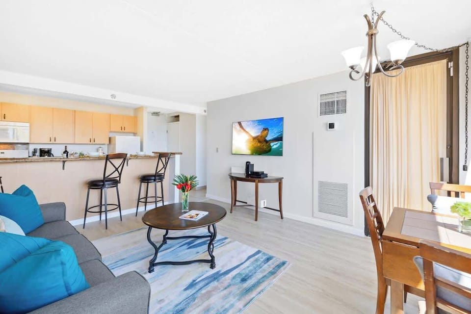 This open-concept living area seamlessly connects the seating space with the adjacent dining table and a convenient breakfast bar leading into the kitchen.
